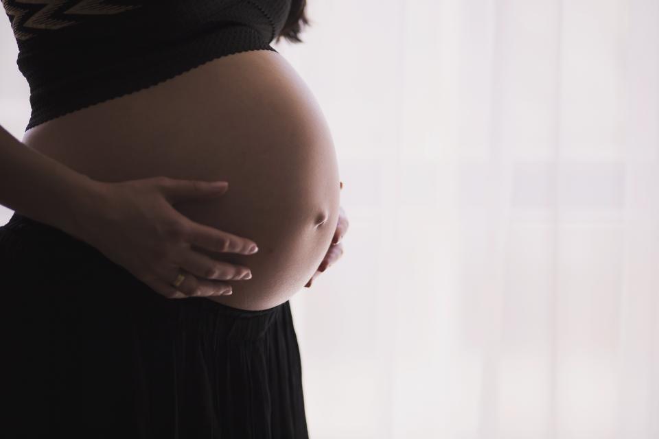 Gravid kvinne fotografert i silhuett mot et lyst vindu